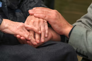 Pfleger hält Klienten Hände