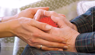 Pflegerin hält Klienten die Hände, in Mitten ein Entspannungsball